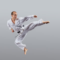 Adult man makes a direct kick on a gray background