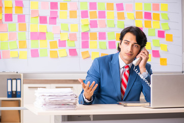 Young handsome employee with many conflicting priorities 