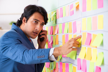 Young handsome employee with many conflicting priorities 