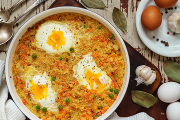 Wheat porridge with vegetables and eggs in a white pan