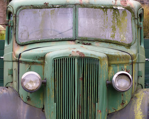 a front view of an old abandoned green rusty 1940s truck