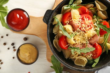 Pan with delicious macaroni, sausage and vegetables on table