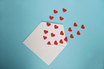 Congratulations on St. Valentine's Day. Many red hearts in a white postal envelope. Blue background. Close-up.  View from above. 