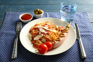 Plate with delicious pasta and sausage on table