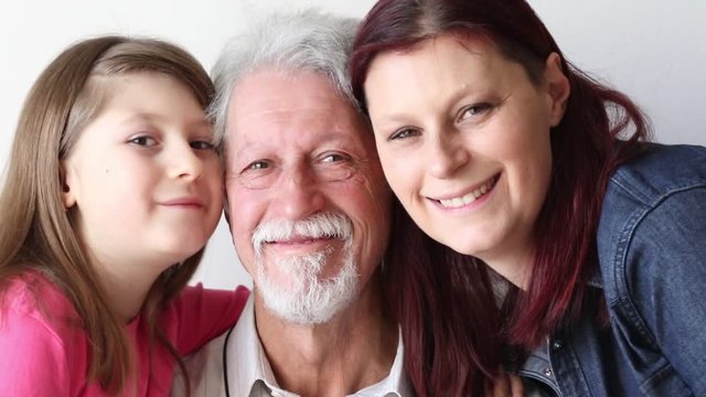 daughter and grandaughter kisses and hugs her grandfather with love