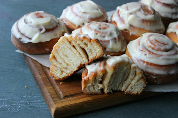 Beautiful fresh cinnamon rolls close-up on wooden grunge texture table. Fragrant homemade cakes, Cinnabon. A Cup of tea on a white saucer, cinnamon sticks. Delicious Breakfast buffet.