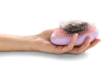 Female hand holding brush with fallen down hair on white background