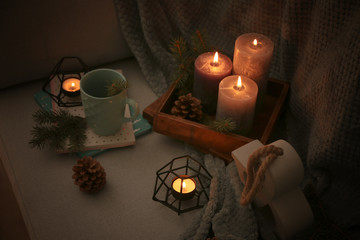 Beautiful burning candles with decor on sofa
