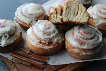 Beautiful fresh cinnamon rolls close-up on wooden grunge texture table. Fragrant homemade cakes, Cinnabon. A Cup of tea on a white saucer, cinnamon sticks. Delicious Breakfast buffet.