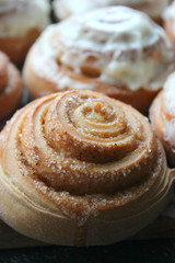 Beautiful fresh cinnamon rolls close-up on wooden grunge texture table. Fragrant homemade cakes, Cinnabon. A Cup of tea on a white saucer, cinnamon sticks. Delicious Breakfast buffet.