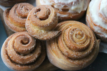 Beautiful fresh cinnamon rolls close-up on wooden grunge texture table. Fragrant homemade cakes, Cinnabon. A Cup of tea on a white saucer, cinnamon sticks. Delicious Breakfast buffet.