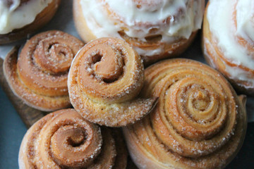 Beautiful fresh cinnamon rolls close-up on wooden grunge texture table. Fragrant homemade cakes, Cinnabon. A Cup of tea on a white saucer, cinnamon sticks. Delicious Breakfast buffet.