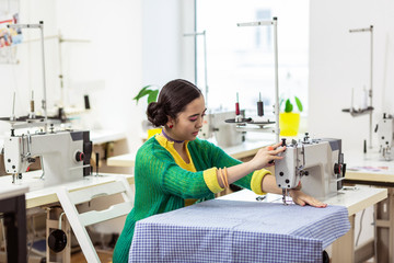 Beautiful brunette asian dressmaker with bright makeup looking serious