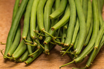 Close up of green beans on a wooden chopping board