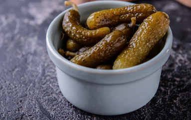 Bowl with tasty fermented cucumbers on grunge table