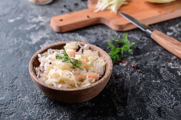 Bowl with tasty fermented cabbage on grunge table