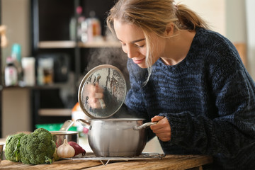 Woman with saucepan of tasty hot soup in kitchen