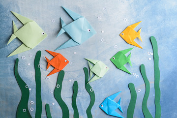 Composition with origami fishes on color background