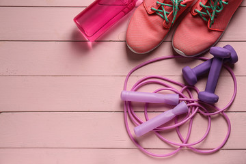 Shoes, sport equipment and bottle of water on color background