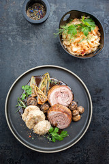 Traditional rolled boar roast with dumpling, fried vegetable and mushroom as top view on a modern design plate with game red wine sauce