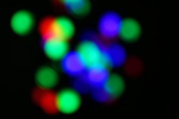 Blurred view of colorful defocused lights on dark background