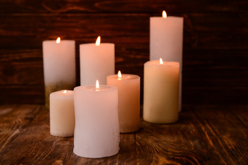 Fototapeta na wymiar Burning wax candles on wooden table