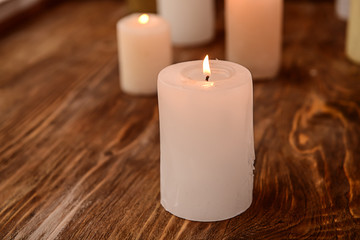 Fototapeta na wymiar Burning wax candle on wooden table