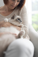 Woman petting her beautiful cat at home