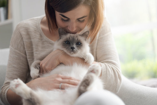 Woman petting her beautiful cat at home