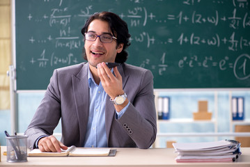 Young handsome math teacher in classroom 