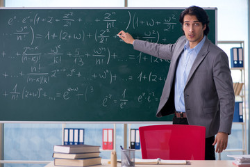 Young handsome math teacher in classroom 