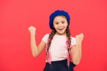 Fashion girl. Fashionable beret accessory. Teenage fashion. French fashion attribute. Child small girl happy smiling baby. Kid little cute fashion girl posing with long braids and hat red background