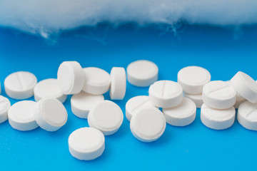 white pills on blue background, medical concept