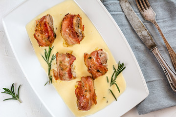 Baked pork tenderloin wrapped in bacon and served in a cheese sauce with rosemary