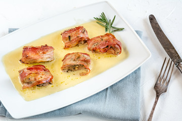 Baked pork tenderloin wrapped in bacon and served in a cheese sauce with rosemary