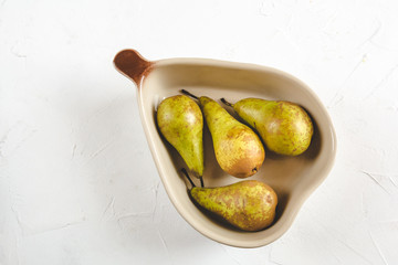 Fresh pears in a dish on a white background