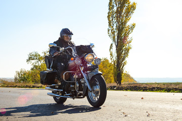 Fototapeta na wymiar Motorcycle Driver Riding Custom Chopper Bike on Autumn highway. Adventure Concept.