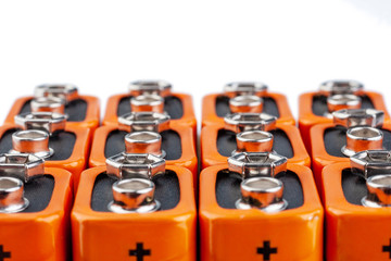 Many orange batteries, stand in several rows.  Isolated on white background