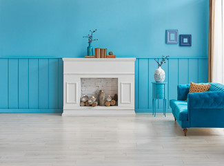 Decorative room, blue wall background and blue sofa style, white fireplace with woods and parquet.
