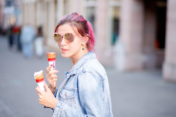 girl with pink hair in denim suit eating delicious ice cream