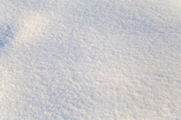 Background of white snow sparkling in the sun. Shallow depth of field