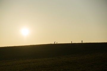 Fototapeta na wymiar People walking on a meadow during sunset. Slovakia 