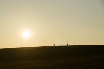 Obraz na płótnie Canvas People walking on a meadow during sunset. Slovakia 