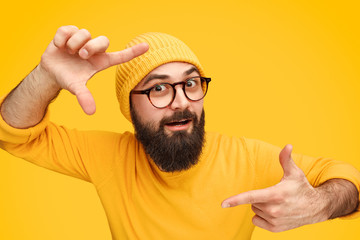 Naklejka premium Bearded man holding hands in shape of camera focus
