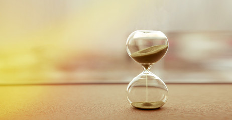 Modern hourglass with sand color background, as time passing concept for business deadline, urgency and running out of time