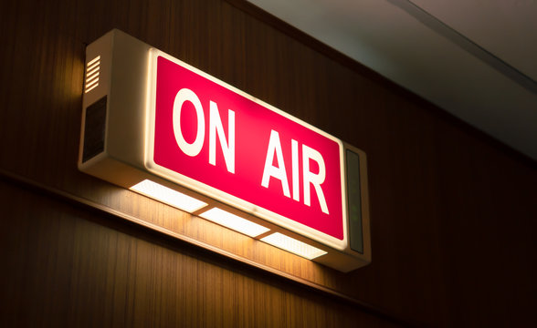 On Air sign icon glowing on the wooden wall of sound recording studios, live broadcast radio production room