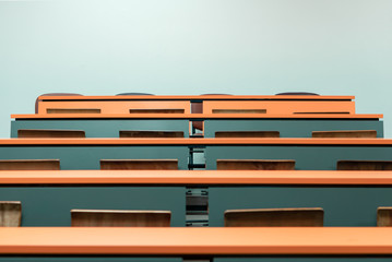 empty student desk with wooden chair in the lecture classroom of college, school education background with copy space wall