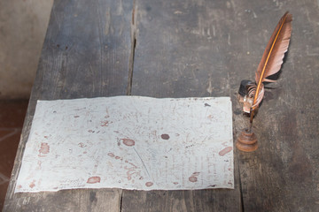 Feather quill and unfinished letter on a wooden desk.
