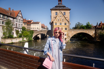 Outdoor Portrait of a beautiful young confident woman posing on the street of Bamberg. Model in stylish sun glasses. Girl looks up. Women's fashion. Sunny day.