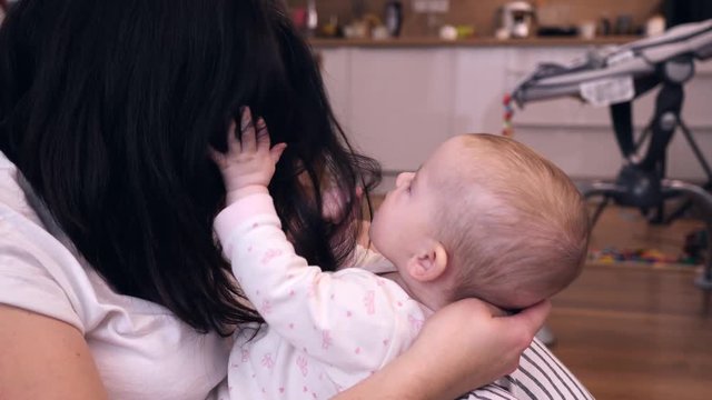 Baby girl child has fun enjoy play try to catch mother brunette hair - happy motherhood